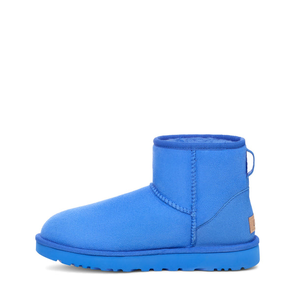 Blue ankle-height boot with a rounded toe and a flat sole on a white background.