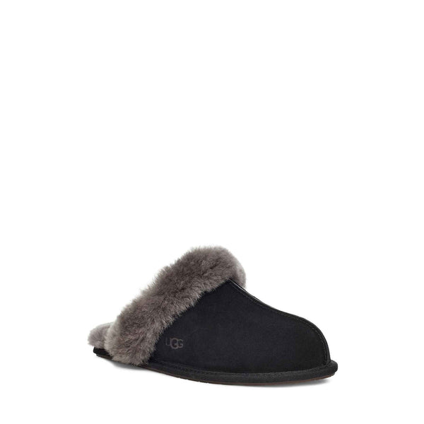 Side view of a single black UGG slipper with fluffy lining on a white background.