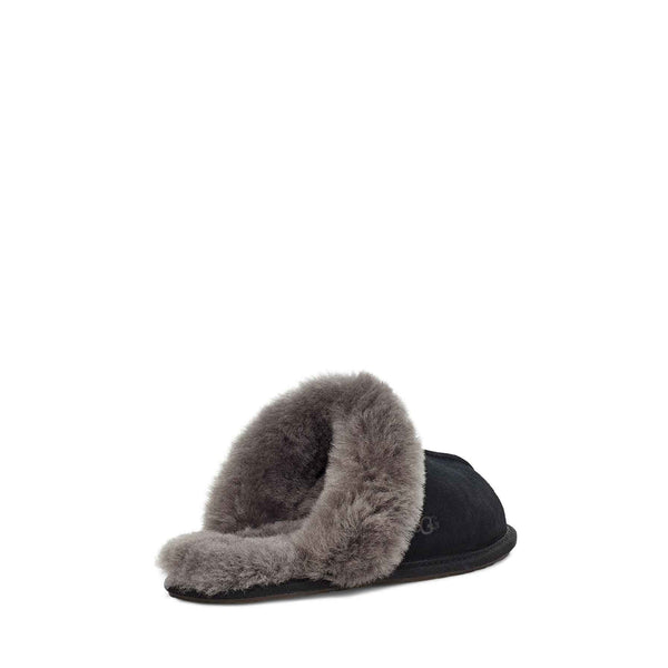 bACK view of a single black UGG slipper with fluffy lining on a white background.