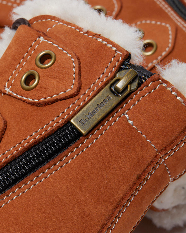 Close-up of a brown boot with fluffy lining and a branded metal zipper.