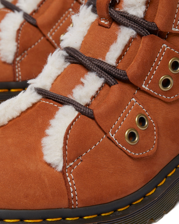 Close-up of a brown winter boot with fuzzy lining and black laces.