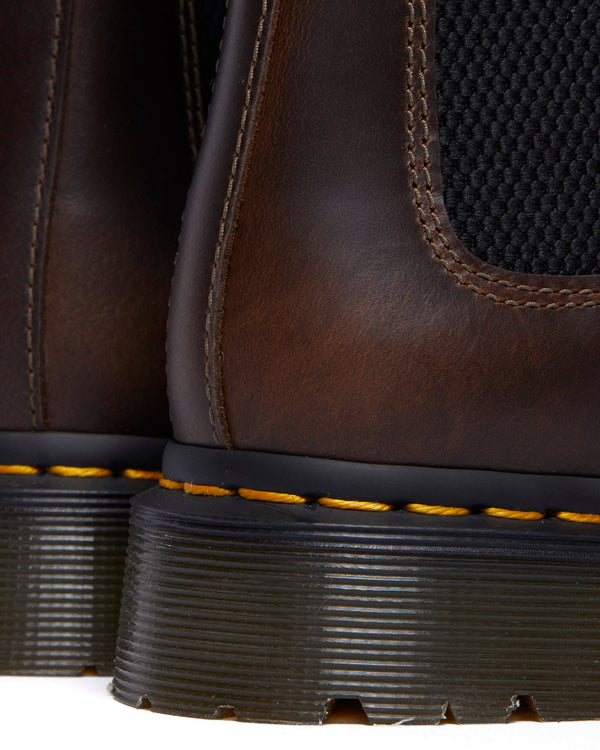 Close-up of brown work boots with yellow stitching on black soles.