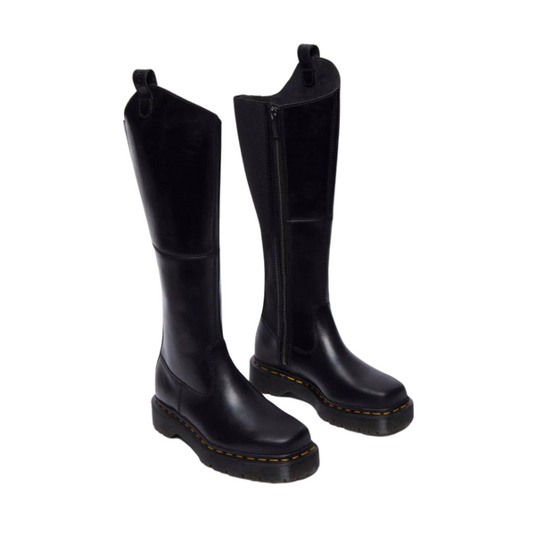 A pair of black leather boots with zippers and yellow stitching on soles, isolated on white background.